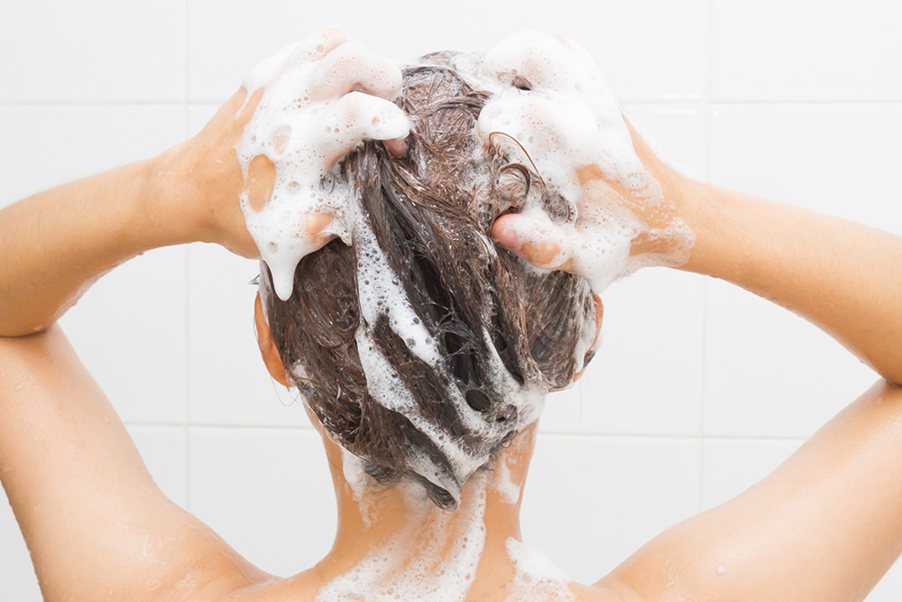 a woman washing her hair with shampoo